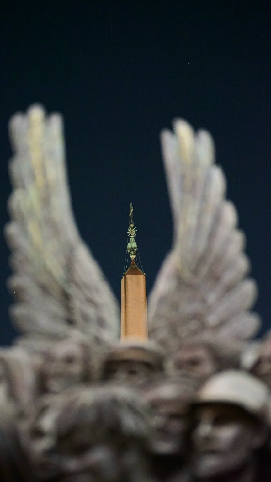 Winged sculpture framing an obelisk at night, photographed by Haytham El Chaer
